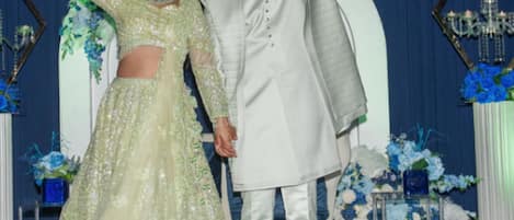 A couple on a stage with a blue backdrop and floral decorations.