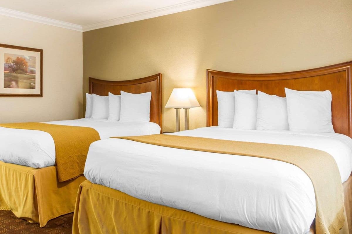 Two single beds with wooden headboards, white bedding, and a yellow throw blanket.