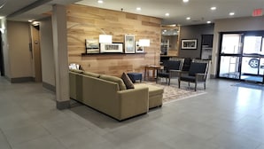A lobby with a beige sofa, two armchairs, a small table, and a rug.