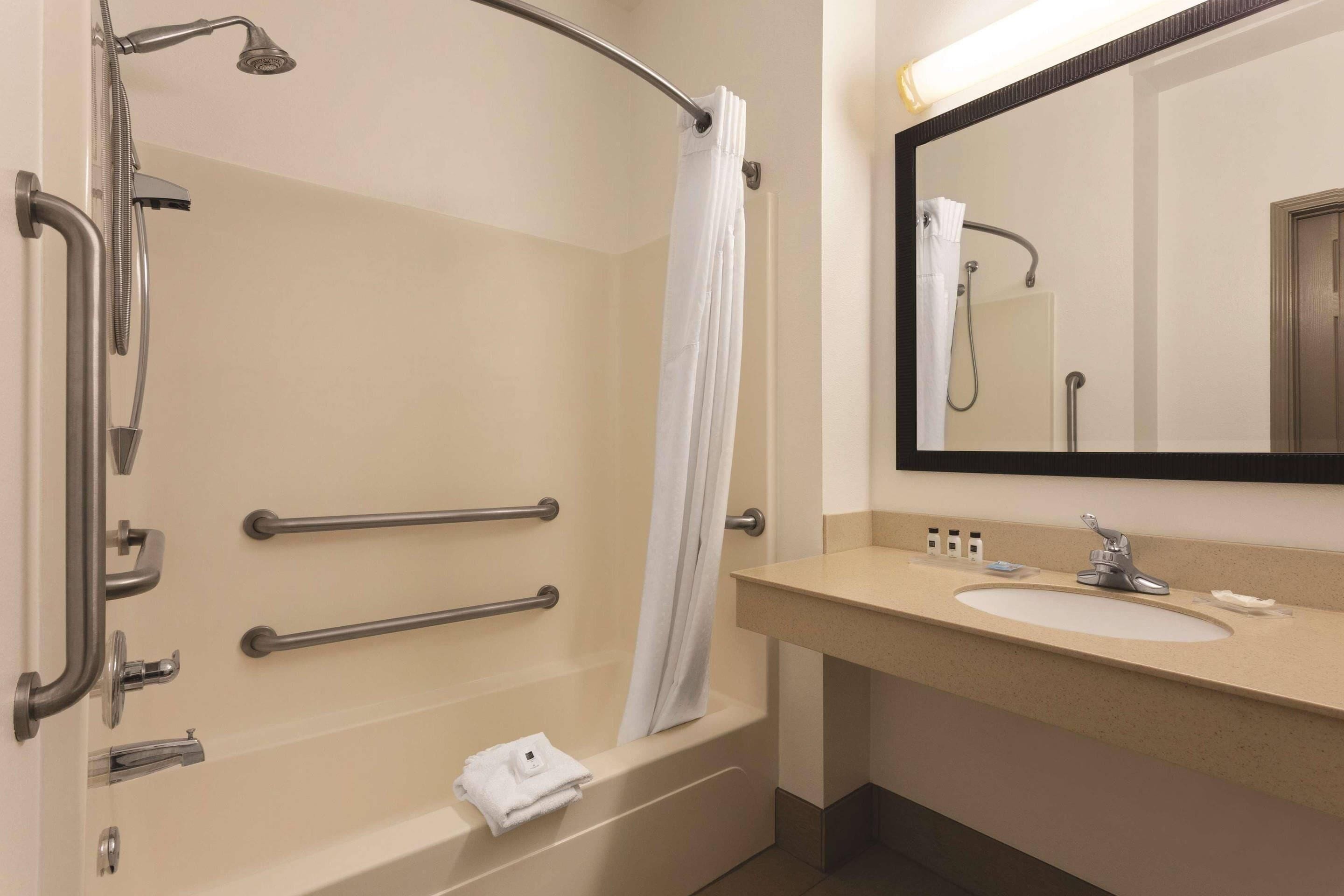 A bathroom with a bathtub, a shower, a sink, and a mirror.