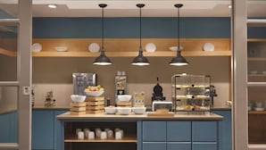 A kitchen area with a central island, wooden shelves, and hanging pendant lights.