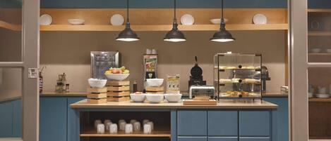 Un área de cocina con una isla central, estantes de madera y lámparas colgantes.
