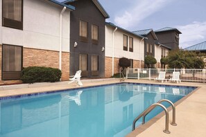 A hotel with a swimming pool, a covered patio, and a brick facade.