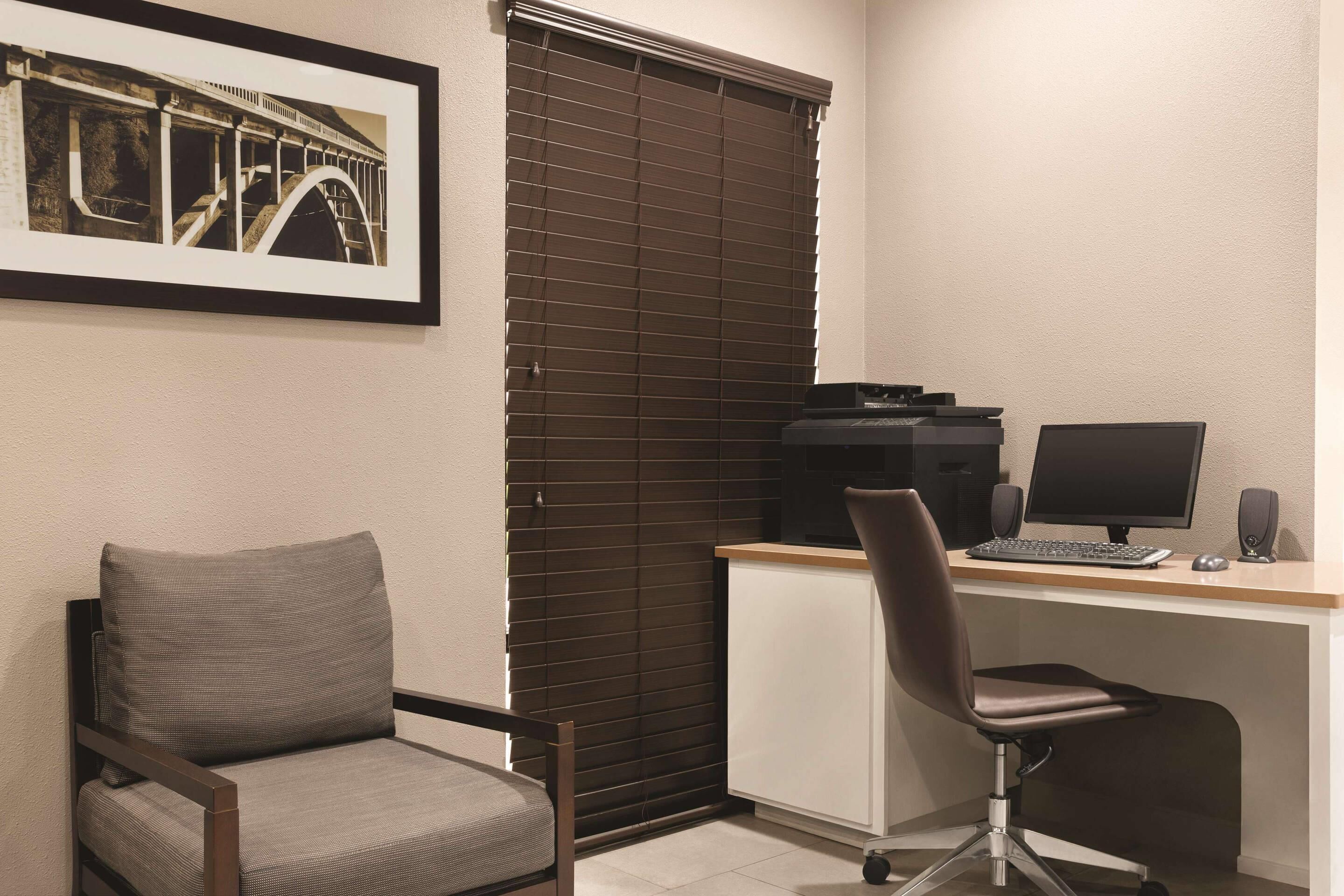 A room with a desk, two chairs, a computer, and a printer.