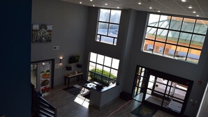 Un amplio vestíbulo de hotel con techos altos, ventanas grandes y una isla central con asientos.
