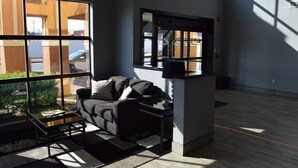 Una sala de estar moderna con un sofá, una mesa de centro y vistas amplias a través de grandes ventanales.