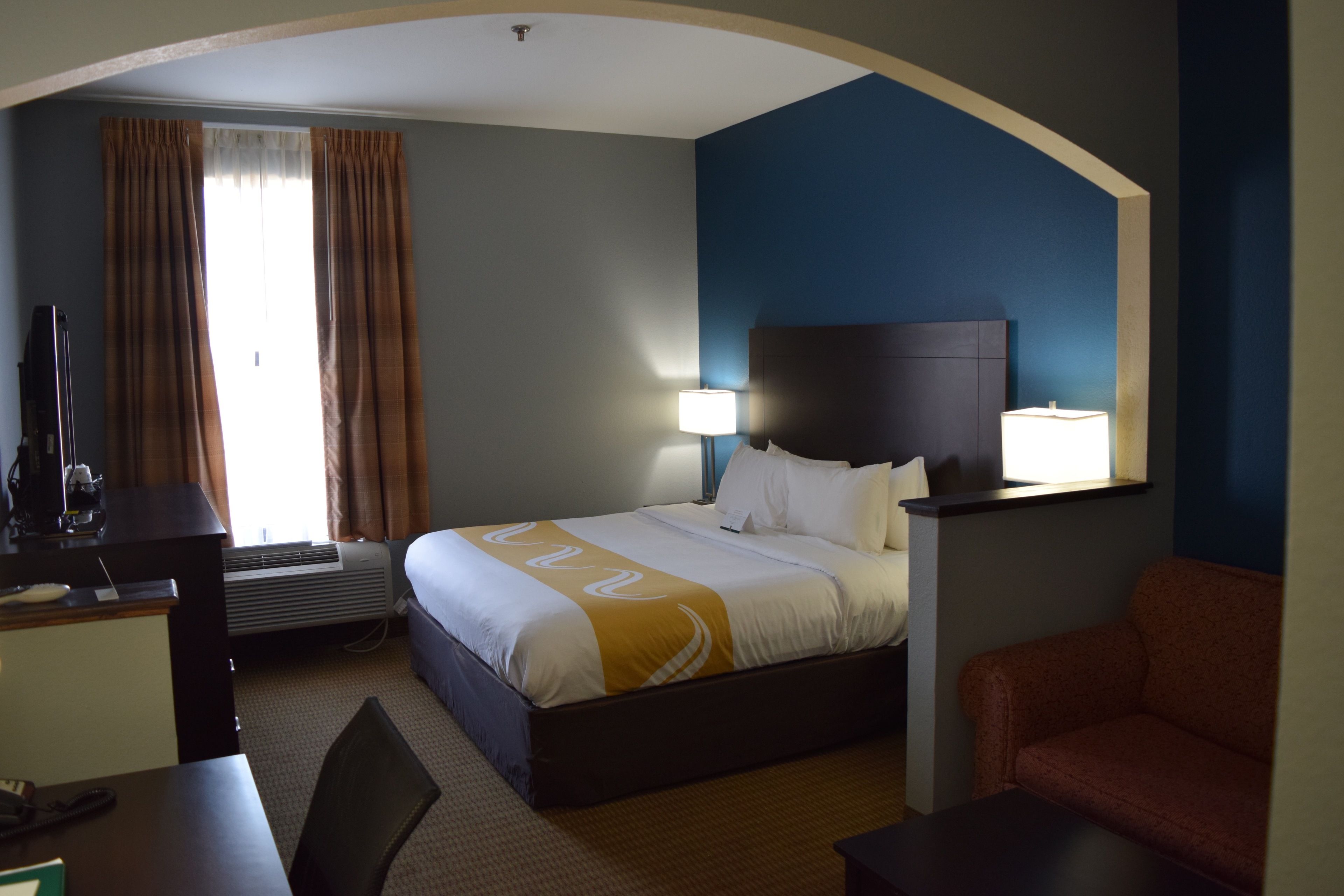Una habitación de hotel con cama, escritorio, silla y sofá.