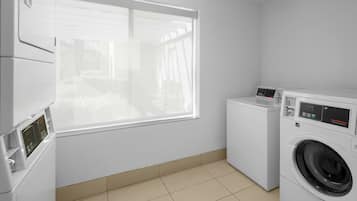 A laundry room with a washing machine, dryer, and stacked washer-dryer units.