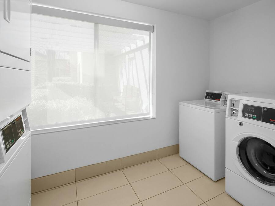 A laundry room with a washing machine, dryer, and stacked washer-dryer units.