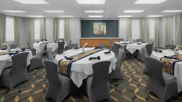 A conference room with round tables, grey chairs, and a patterned carpet.