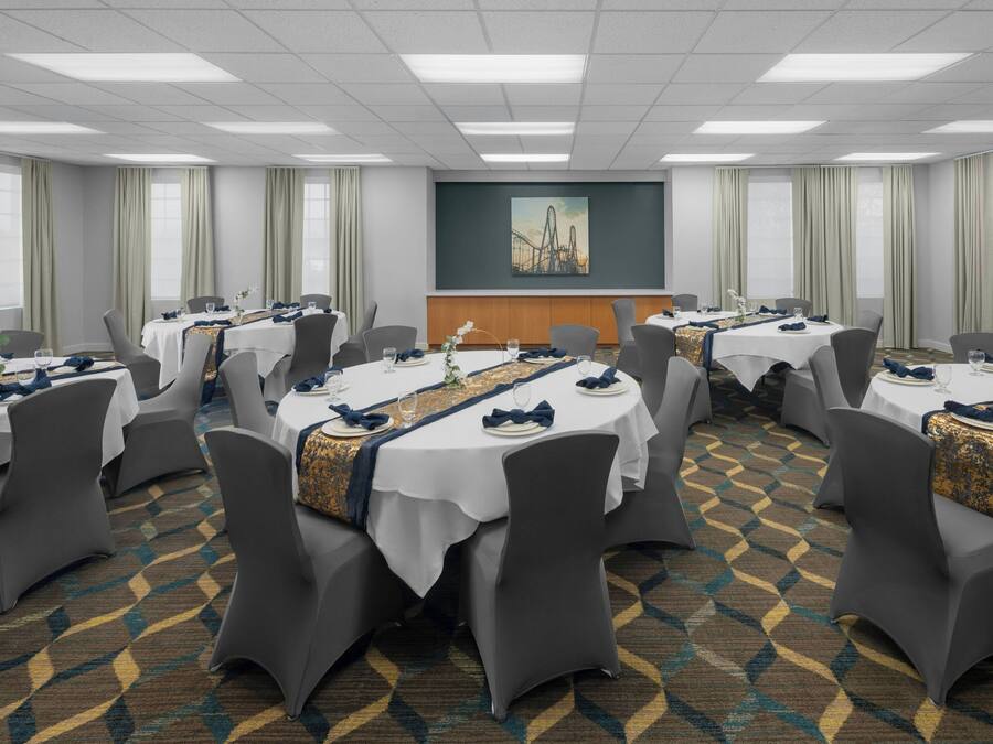 A conference room with round tables, grey chairs, and a patterned carpet.