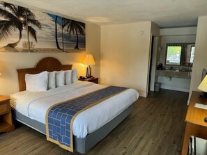 Relax in this inviting room with a large bed, wooden headboard, and a kitchenette.
