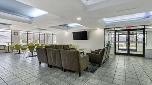 A spacious lobby with a high ceiling, a flat-screen TV mounted on the wall, and a seating area with sofas and chairs. - Rodeway Inn Wesley Chapel (Wesley Chapel)