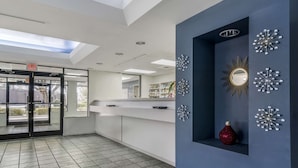 A modern lobby with a glass door entrance, a reception desk, and decorative wall art. - Rodeway Inn Wesley Chapel (Wesley Chapel)