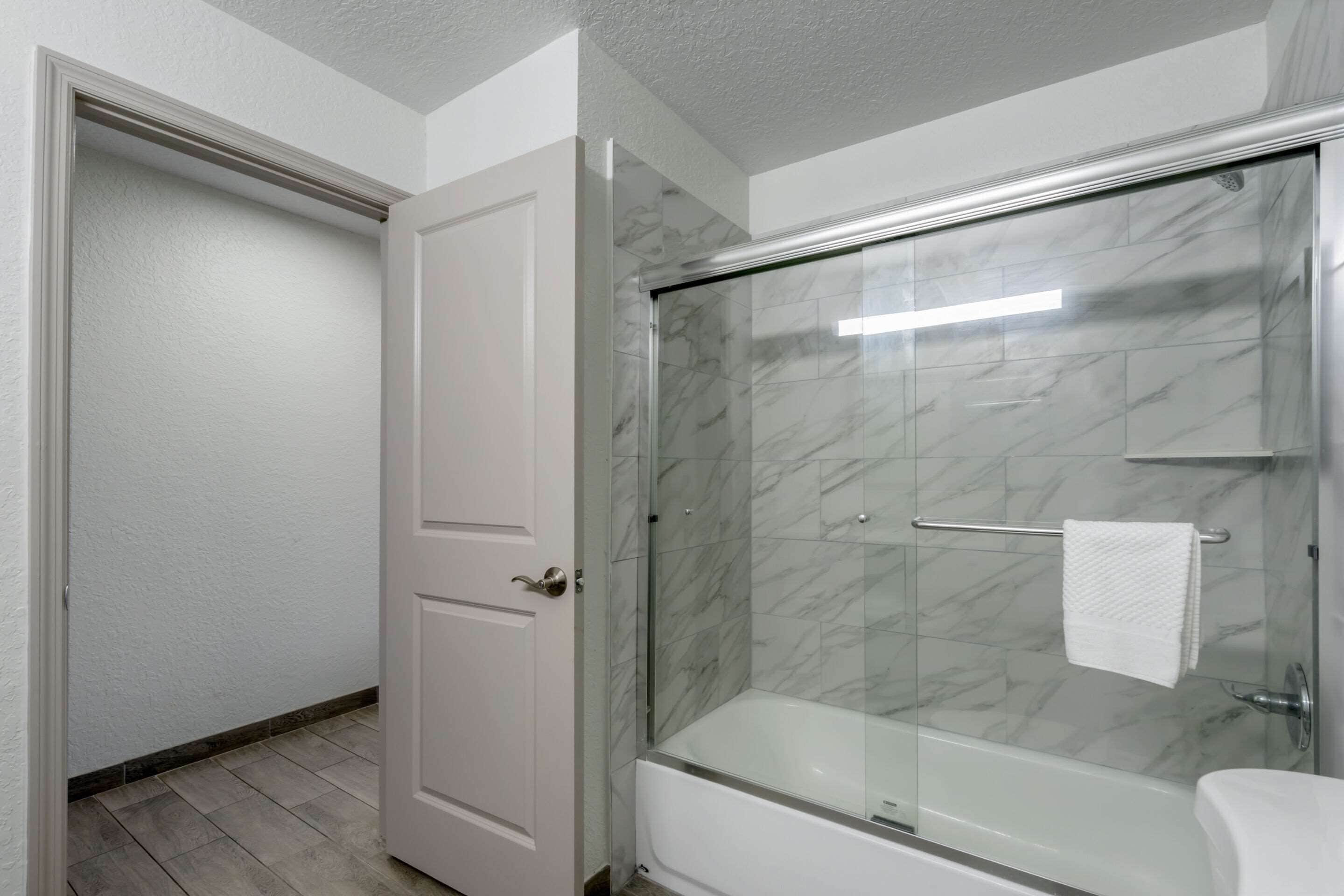 A bathroom with a glass-enclosed shower, a white bathtub, and a white toilet.