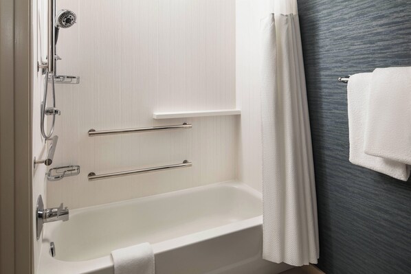 Un baño moderno con una bañera blanca, ducha y toallero.