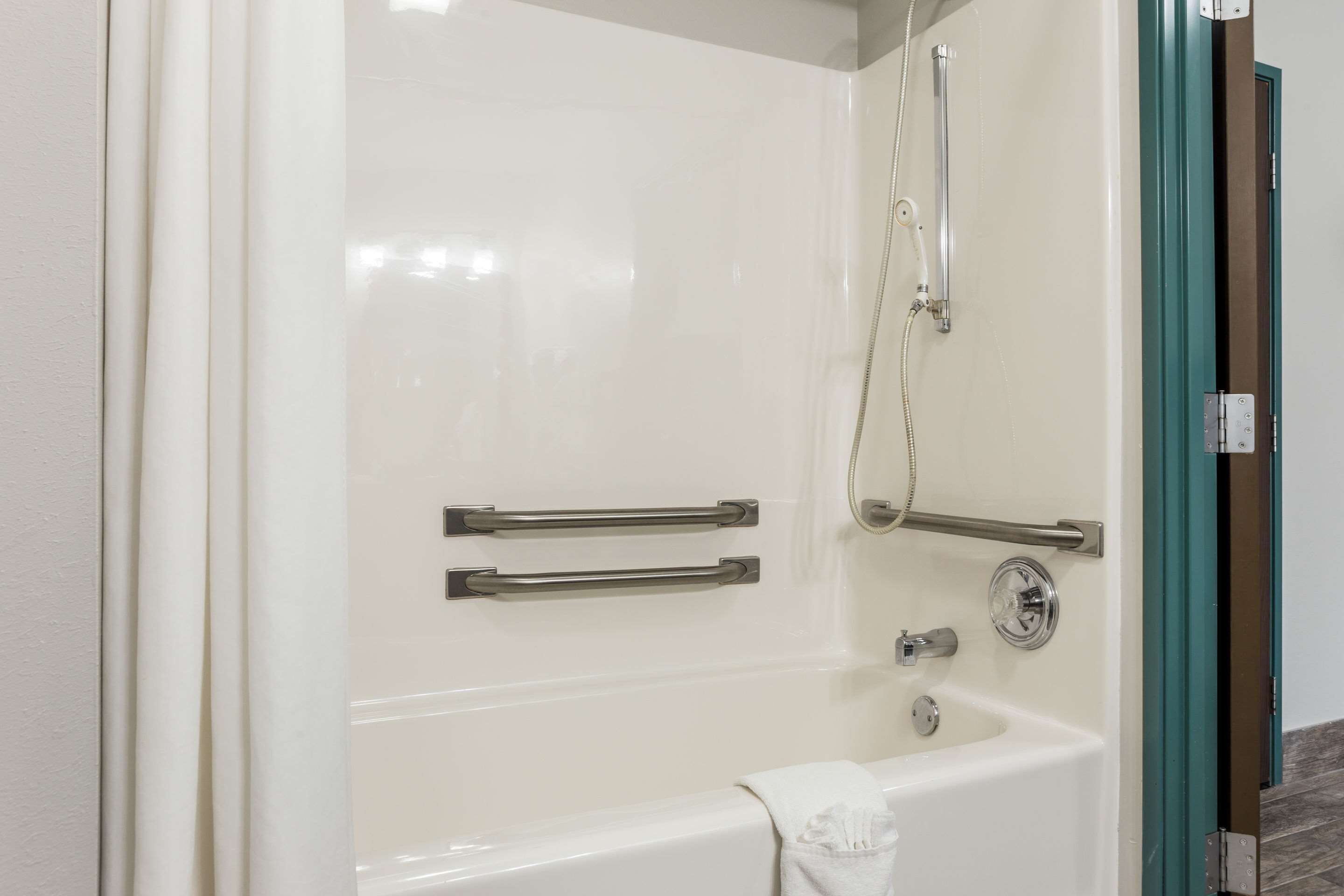 Un baño moderno con bañera, ducha y dos barras de apoyo.