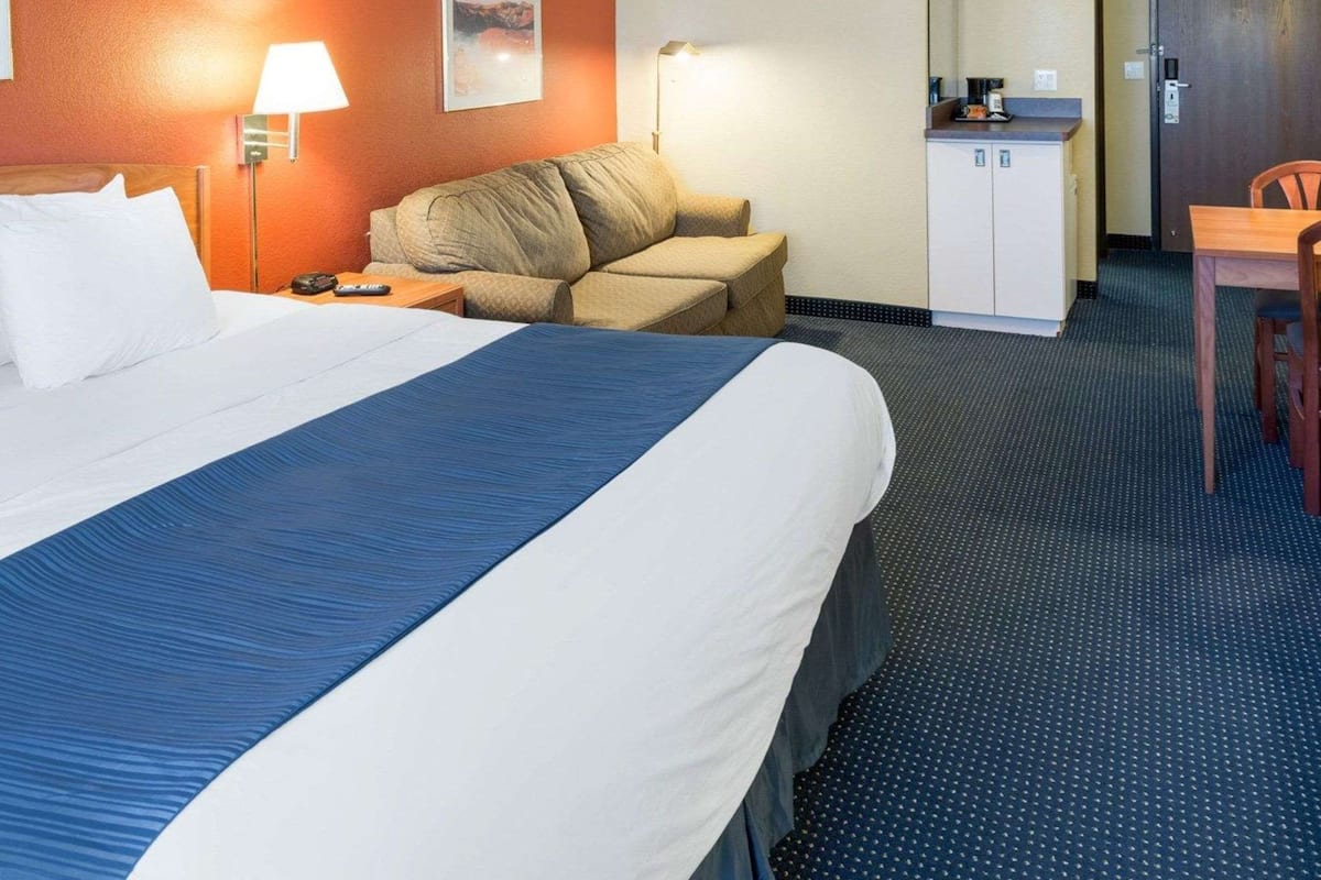 Une chambre d’hôtel avec un grand lit, un canapé, un bureau et un miroir.