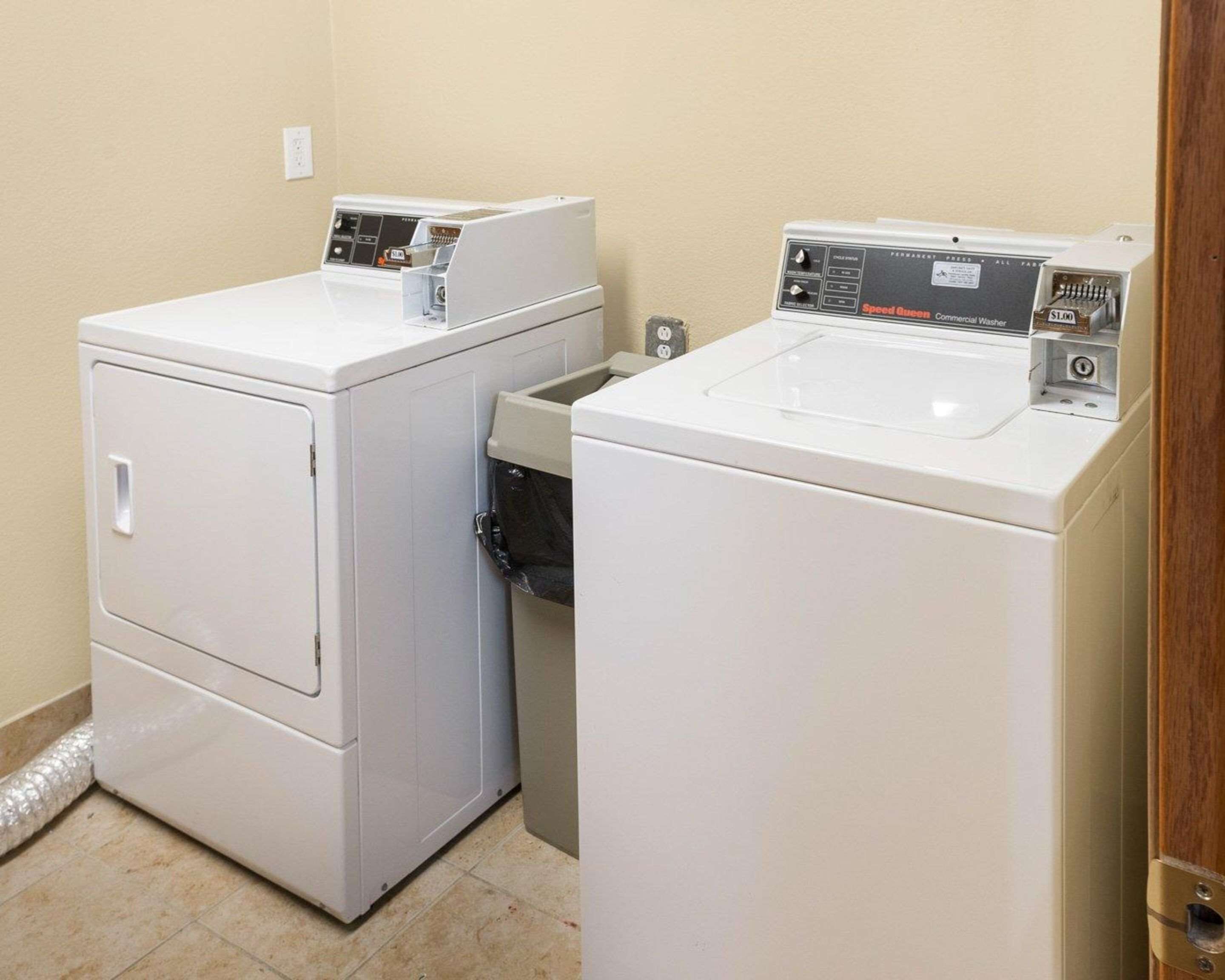 A laundry room with two white front-loading washing machines and a dryer.