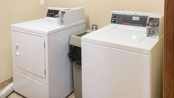 A laundry room with two white front-loading washing machines and a dryer.