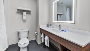 A modern bathroom with a white toilet, a sink with a mirror, and a towel rack.