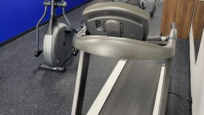 A gym with stationary bikes, a treadmill, and a water dispenser.