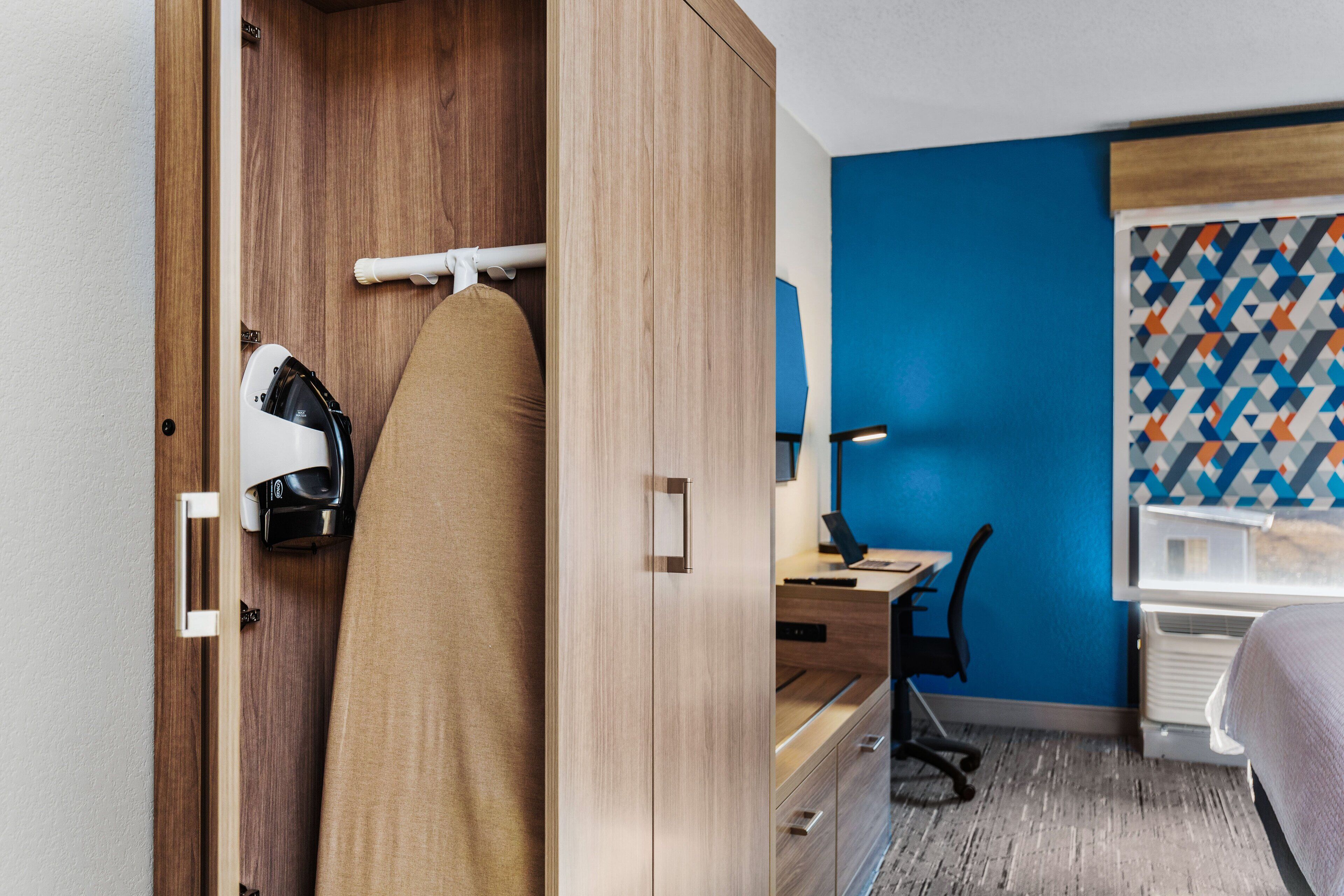 Una habitación de hotel con un armario de madera, un escritorio con una silla y una cama.