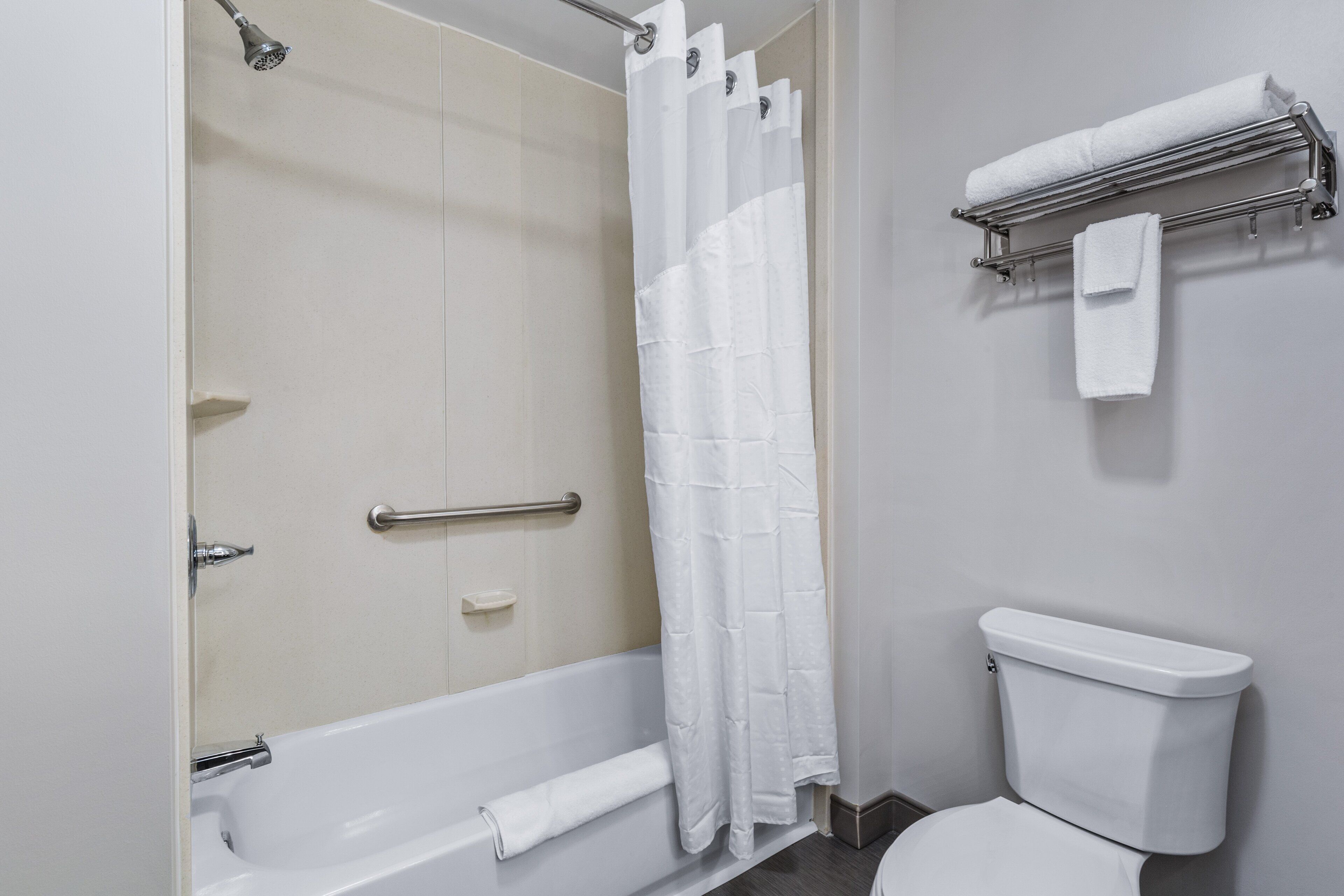 A bathroom with a bathtub, shower, toilet, and towel rack.