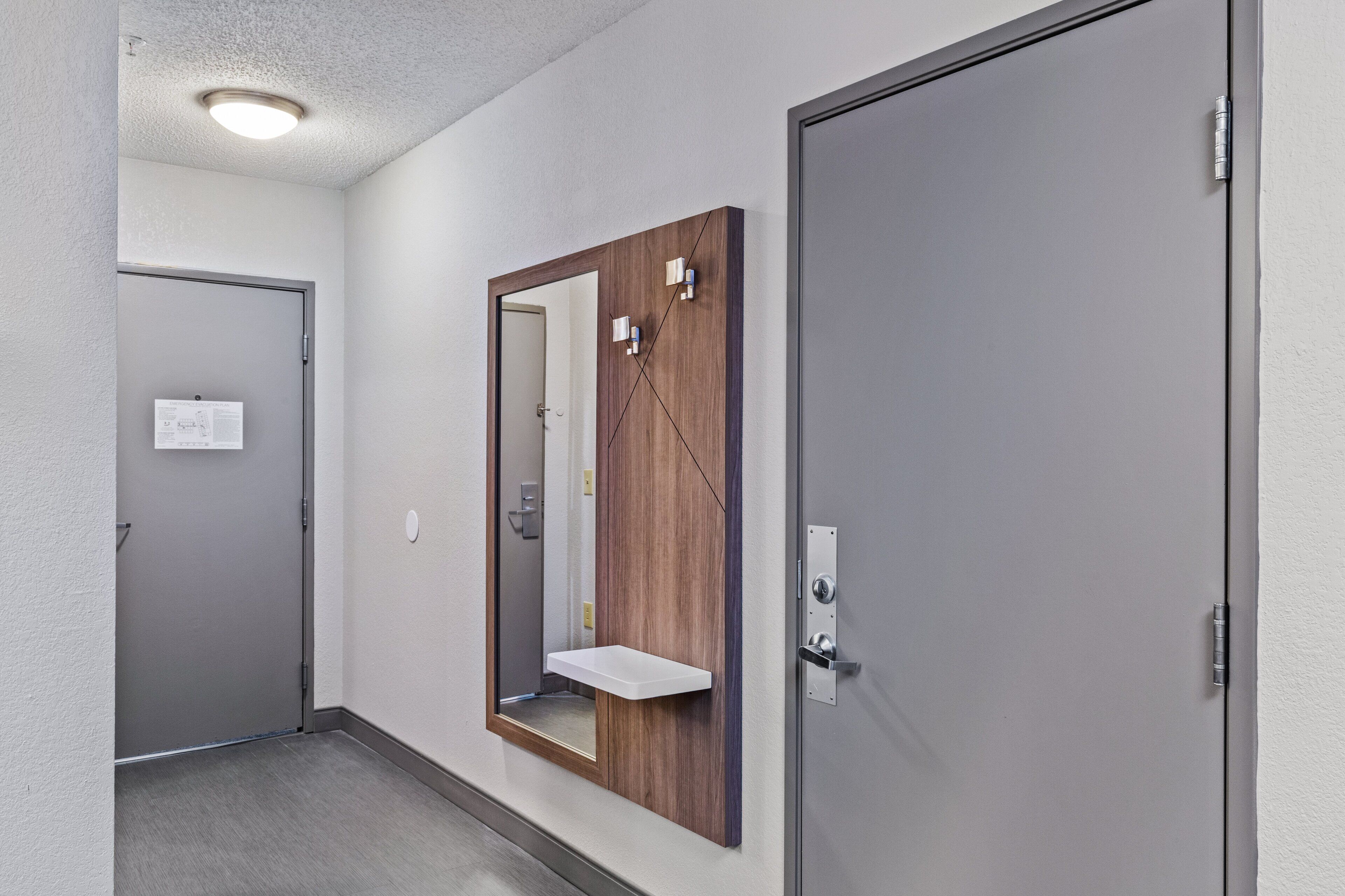 A hallway with a door, a mirror, and a light fixture.