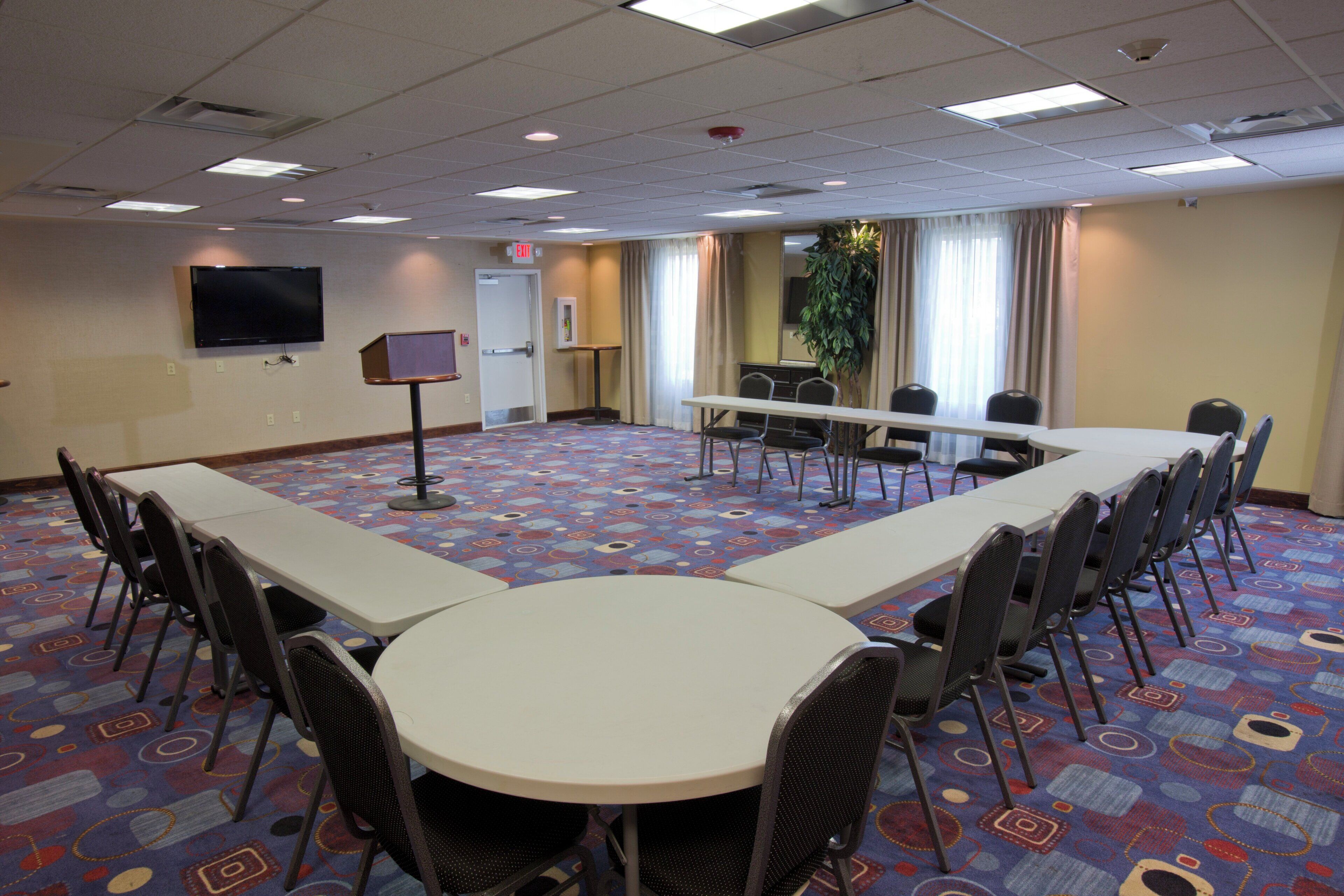 A conference room with a long table, chairs, a television, and a door marked 'EXIT'.