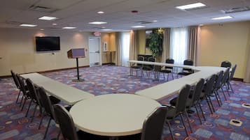 A conference room with a long table, chairs, a television, and a door marked 'EXIT'.
