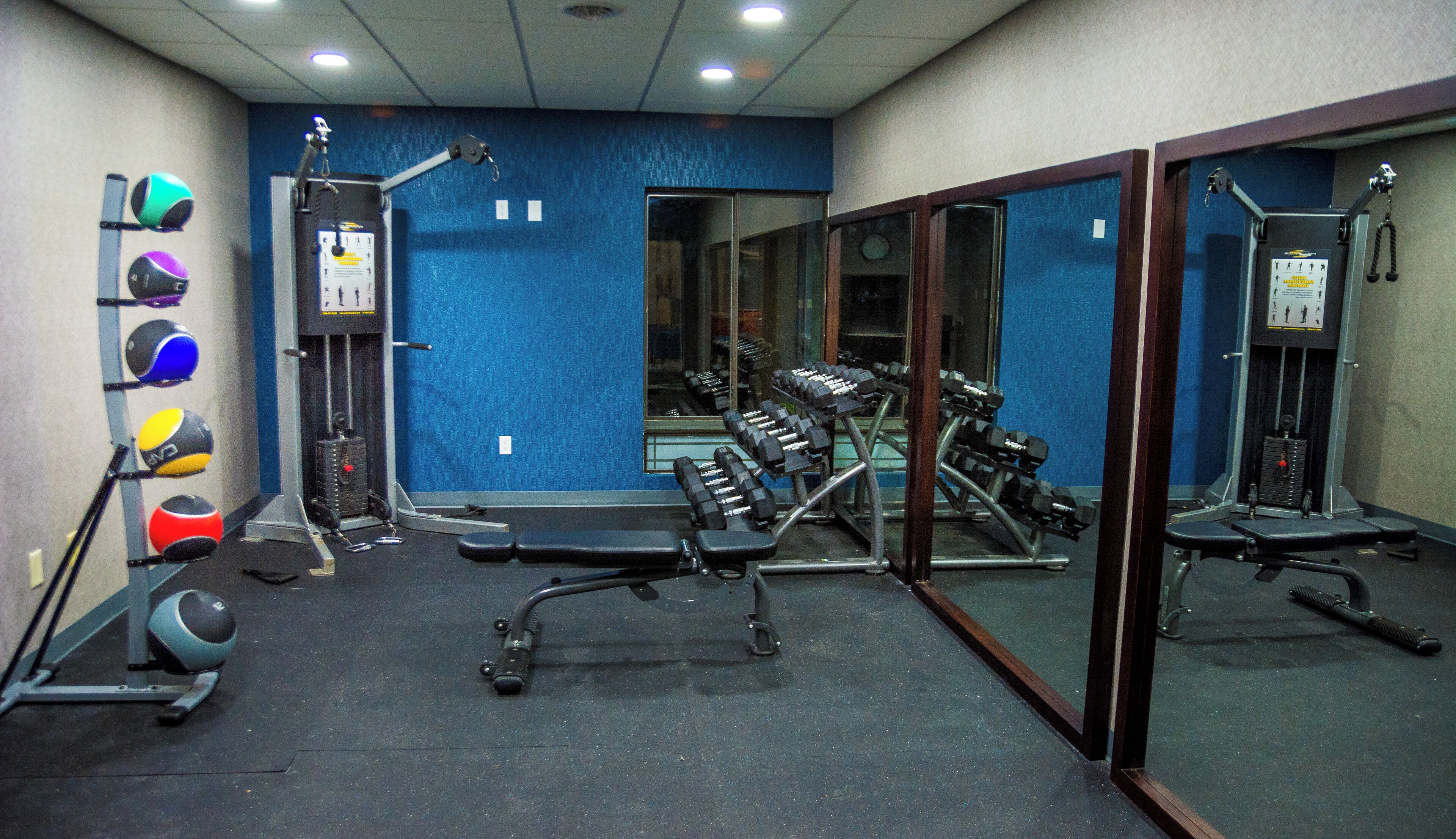 A gym with exercise equipment, a bench, and a mirror.
