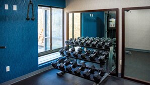 A gym with blue walls, a window, and a rack of dumbbells. - La Quinta Inn & Suites by Wyndham Fayetteville I-95 (Fayetteville)