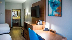 A hotel room with a bed, a desk with a chair, a television, and a painting on the wall. - La Quinta Inn & Suites by Wyndham Fayetteville I-95 (Fayetteville)