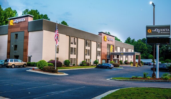 A hotel with a modern facade, multiple entry points, and a parking lot.