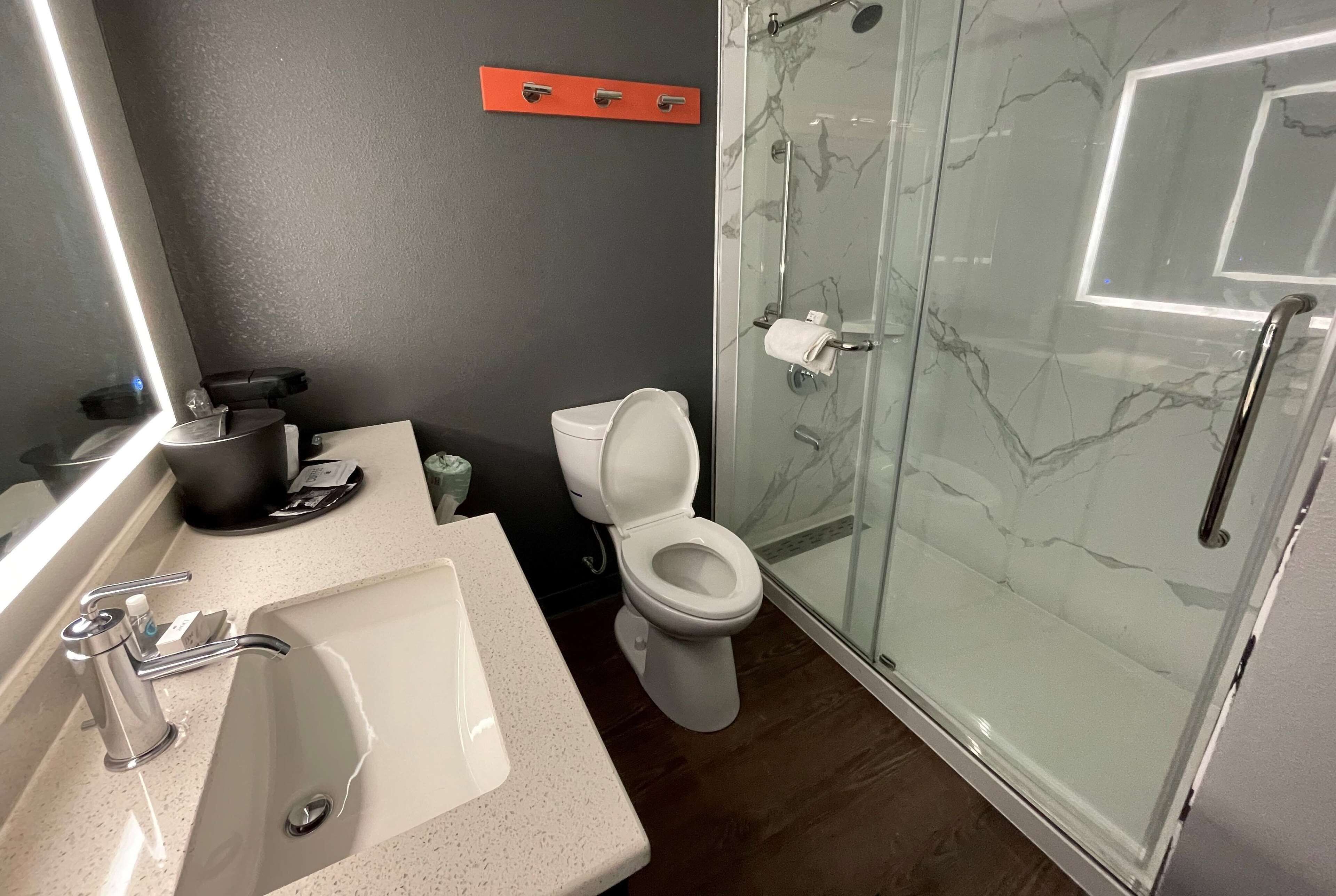 Un baño moderno con cabina de ducha de vidrio, un lavabo blanco y un inodoro.