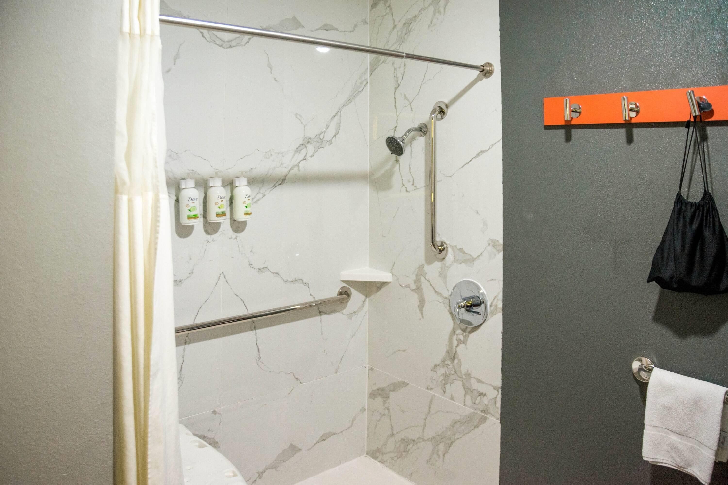 Un baño con ducha, toallero y artículos de aseo en la pared.