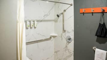 Un baño con ducha, toallero y artículos de aseo en la pared.
