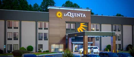Un hotel La Quinta con una fachada moderna, un estacionamiento y cielo despejado.