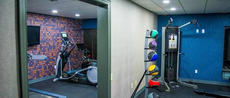 Et fitnessrum med løbebånd, en motionscykel og et styrketræningsområde.