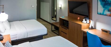 Habitación de hotel con dos camas, un escritorio, un televisor y un espejo.