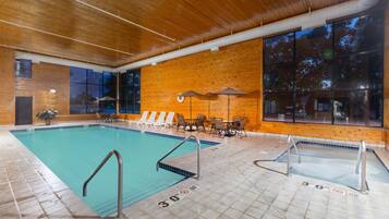 An indoor swimming pool with clear water, wooden walls, and a tiled floor.