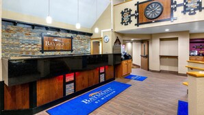 Een receptie met een Baymont by Wyndham bord, een klok en een keuken in de achtergrond.
