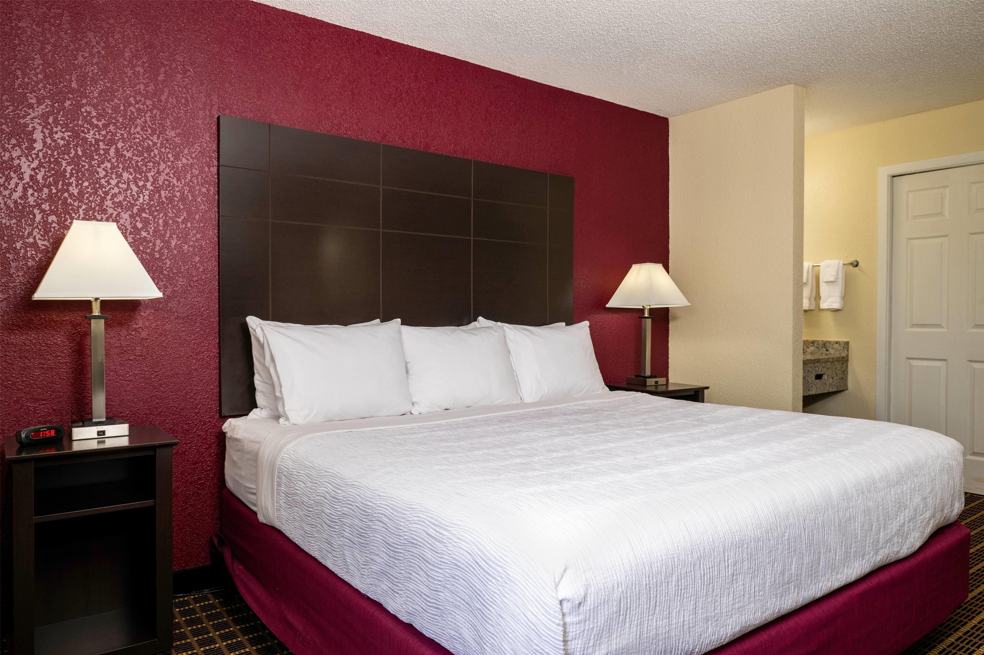 A hotel room with a large bed, two bedside tables, and a headboard.