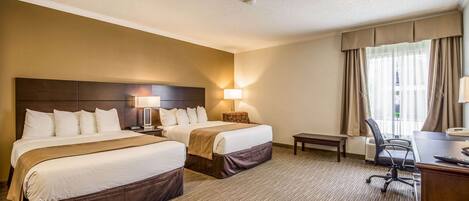 A hotel room with two beds, a desk, a chair, and a small table.