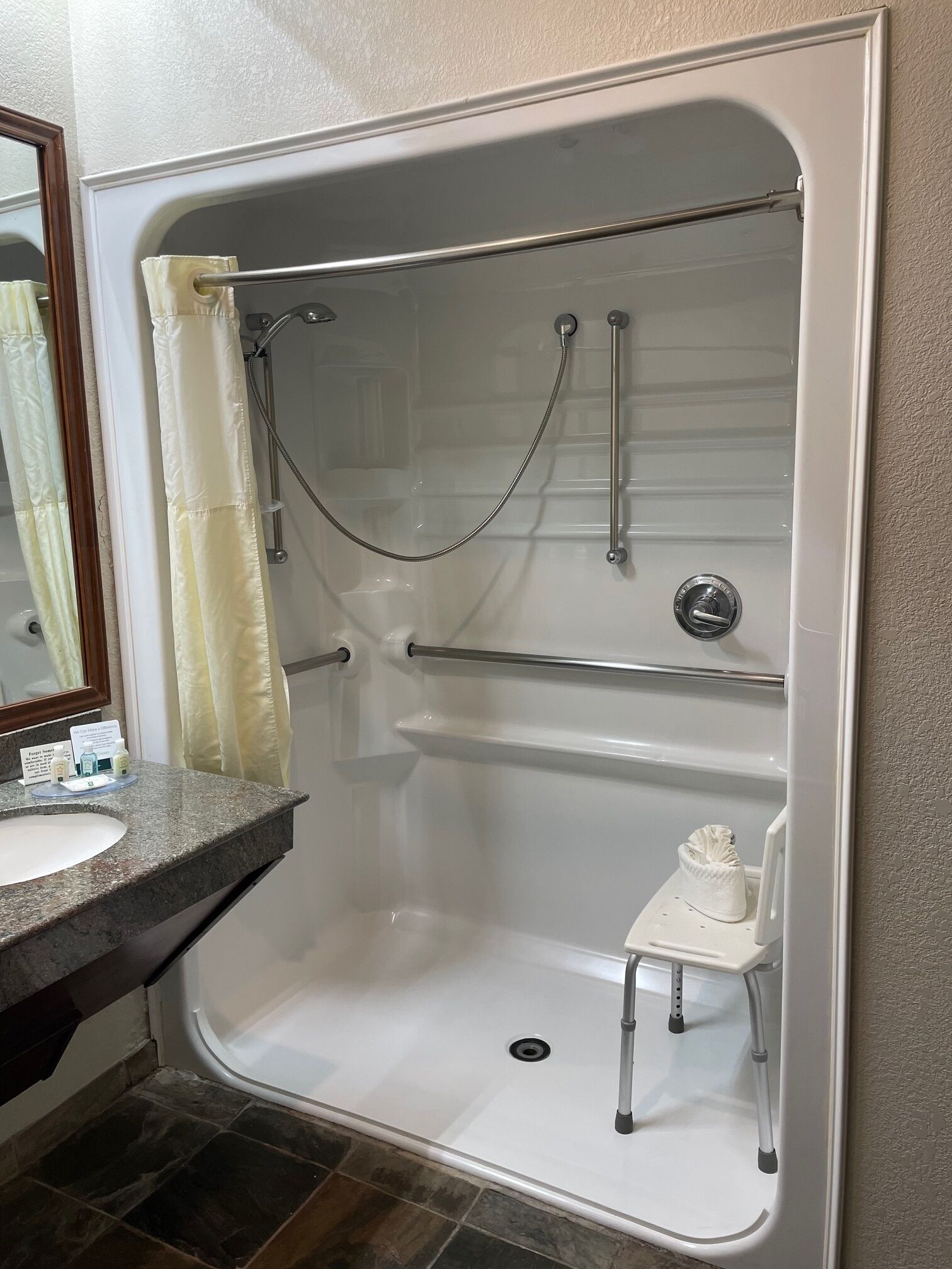Een moderne badkamer met een bad, een douche en een klein krukje.