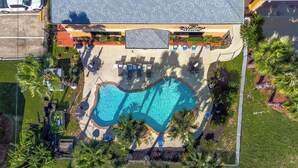 An aerial view of a resort with a swimming pool, lounge chairs, and palm trees. - Quality Inn & Suites Seabrook - NASA - Kemah (Seabrook)
