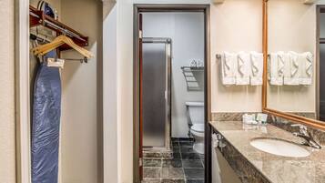 Un baño con lavamanos, espejo y toallas colgadas en la pared.