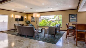 A spacious lobby with a large window offering a view of greenery, a seating area with chairs and a sofa, and a dining table with chairs. - Quality Inn & Suites Seabrook - NASA - Kemah (Seabrook)