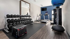 Un gimnàs modern amb equips de musculació, cintes de córrer i pilotes d'exercici.